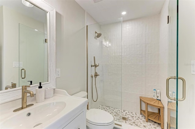 bathroom with vanity, toilet, and a shower with door