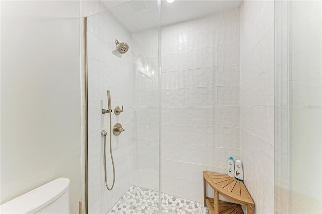 bathroom featuring toilet and a shower with door