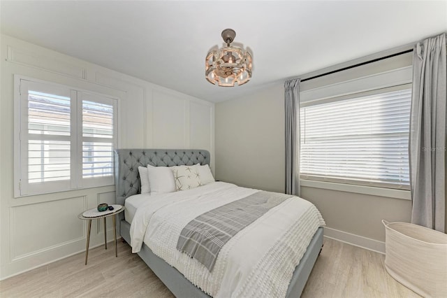 bedroom with light wood-type flooring and a notable chandelier