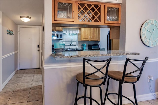 kitchen featuring a breakfast bar, light tile patterned flooring, and light stone countertops