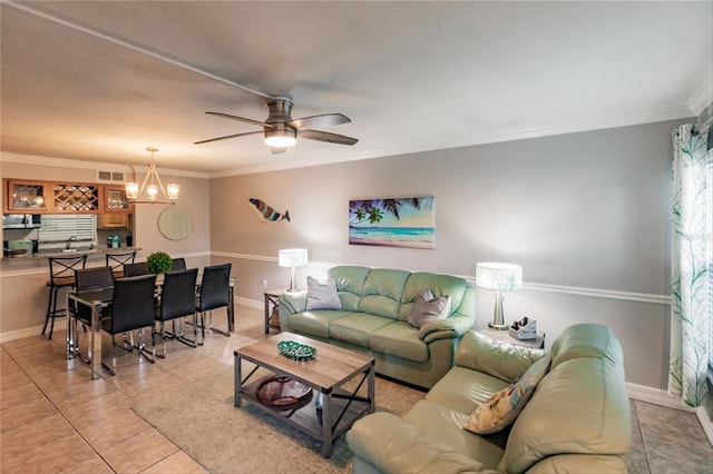 tiled living room with ceiling fan with notable chandelier and ornamental molding