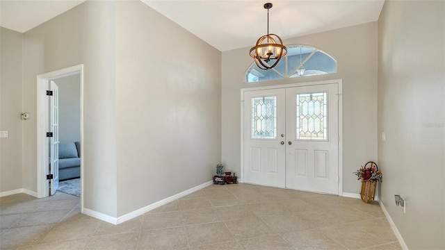 foyer entrance with lofted ceiling, light tile patterned floors, a notable chandelier, and french doors