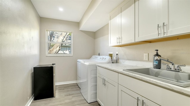 laundry area with sink, light wood-type flooring, washer and clothes dryer, and cabinets