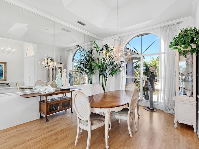 dining room with ornamental molding, light wood-type flooring, and an inviting chandelier