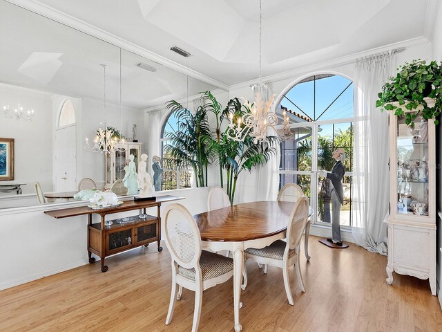 508 Siesta Dr, Sarasota, FL 34242 - dining room featuring a chandelier, light wood-type flooring, a tray ceiling, and ornamental molding