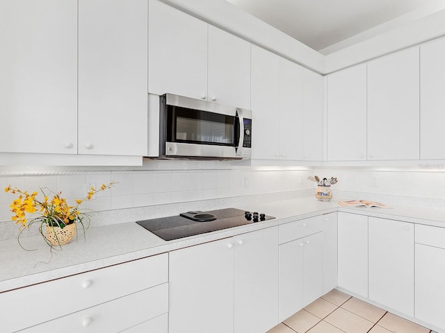 kitchen with white cabinets, decorative backsplash, black electric cooktop, and light tile patterned flooring