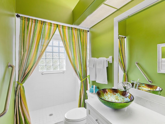 bathroom with a tile shower, vanity, and toilet