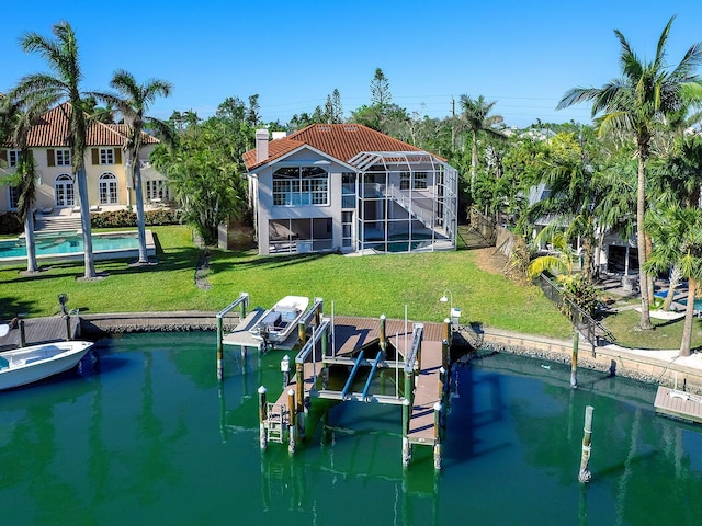 rear view of house with a lanai, a yard, and a water view