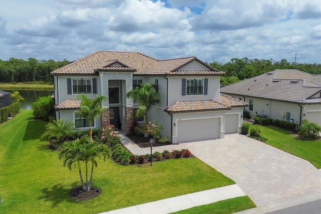 mediterranean / spanish home with a front yard, a water view, and a garage