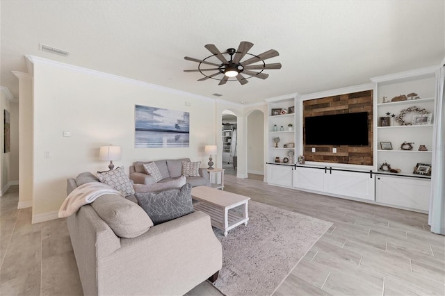 living room with built in shelves, crown molding, light hardwood / wood-style flooring, and ceiling fan