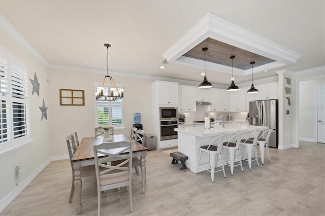 kitchen featuring white cabinets, pendant lighting, stainless steel appliances, and a center island with sink