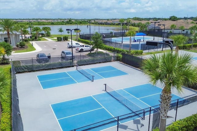 view of sport court featuring basketball hoop and a water view