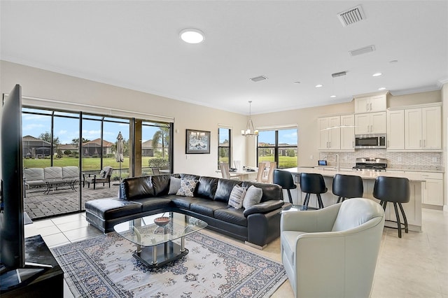 living room featuring light tile patterned floors, an inviting chandelier, crown molding, and sink