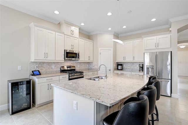 kitchen featuring backsplash, light stone counters, stainless steel appliances, a kitchen island with sink, and wine cooler