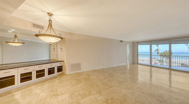 unfurnished living room with a water view, baseboards, visible vents, and crown molding