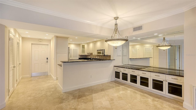 kitchen with visible vents, dark countertops, stainless steel microwave, hanging light fixtures, and white cabinetry