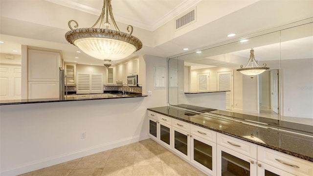 kitchen with glass insert cabinets, dark stone counters, pendant lighting, and white cabinetry