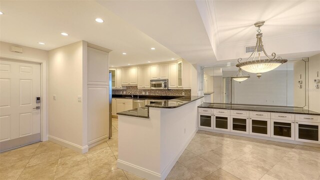 kitchen with a peninsula, stainless steel appliances, white cabinetry, tasteful backsplash, and pendant lighting