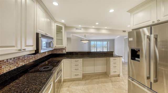 kitchen with appliances with stainless steel finishes, dark stone counters, and white cabinetry