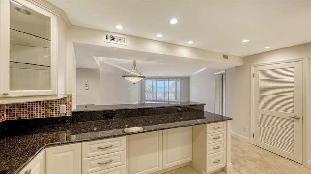 kitchen with visible vents, glass insert cabinets, dark stone countertops, and decorative light fixtures