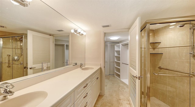 bathroom featuring a stall shower, a sink, visible vents, and a walk in closet