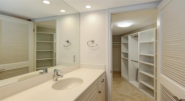 bathroom featuring a spacious closet, vanity, and recessed lighting