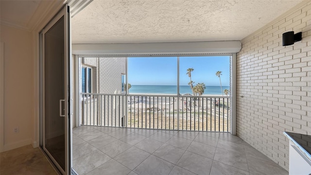 unfurnished sunroom featuring a water view and a view of the beach