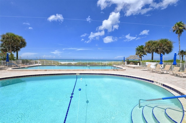 community pool featuring a patio area, fence, and a water view