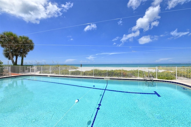 community pool with a water view and fence