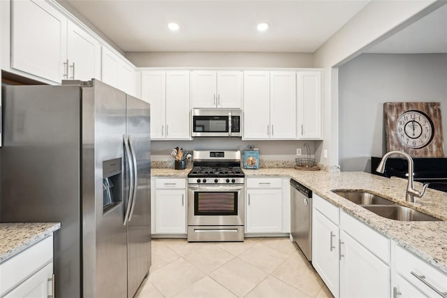 kitchen with light stone countertops, stainless steel appliances, white cabinetry, and sink