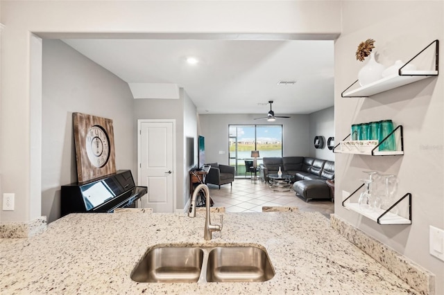 kitchen with ceiling fan, sink, light tile patterned floors, and light stone countertops