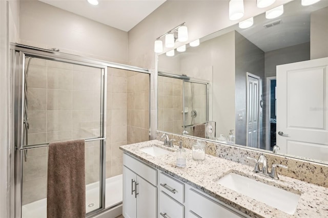 bathroom featuring a shower with door and vanity