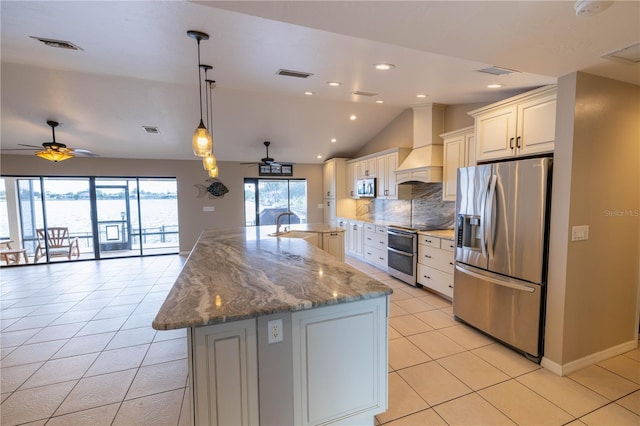 kitchen with ceiling fan, light stone countertops, premium range hood, lofted ceiling, and appliances with stainless steel finishes