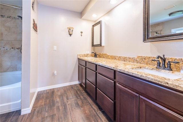 bathroom with hardwood / wood-style floors, vanity, and tiled shower / bath combo