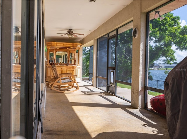 unfurnished sunroom featuring plenty of natural light, ceiling fan, and a water view