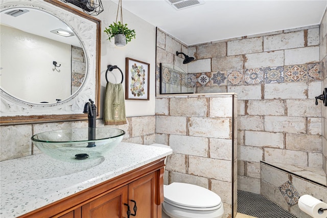 bathroom with a tile shower, vanity, and toilet