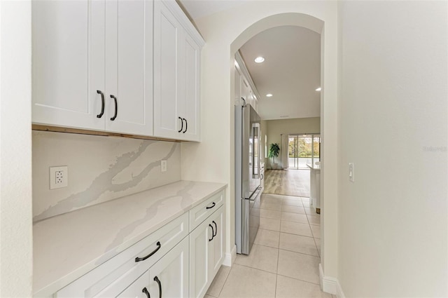 bar featuring light stone countertops, light tile patterned floors, white cabinetry, and high end fridge