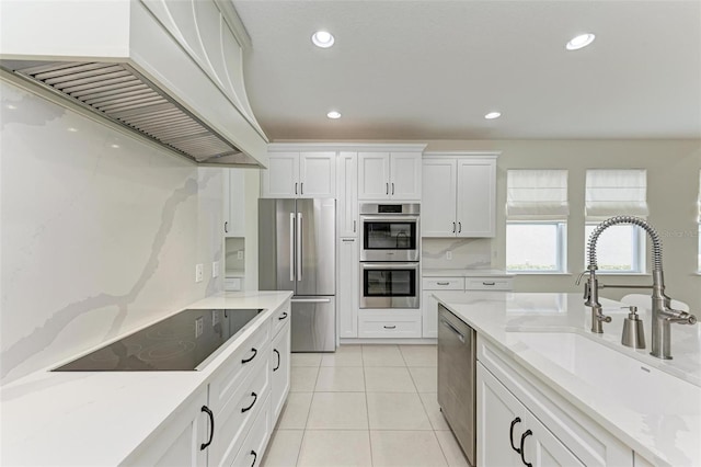 kitchen featuring light stone countertops, sink, stainless steel appliances, white cabinets, and custom exhaust hood