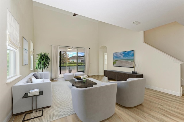 living room featuring light wood-type flooring and a high ceiling