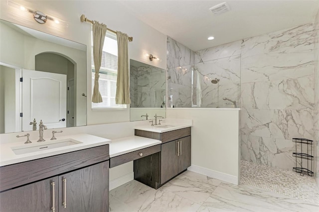 bathroom with a tile shower and vanity