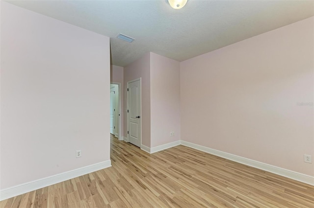 unfurnished room with light wood-type flooring and a textured ceiling