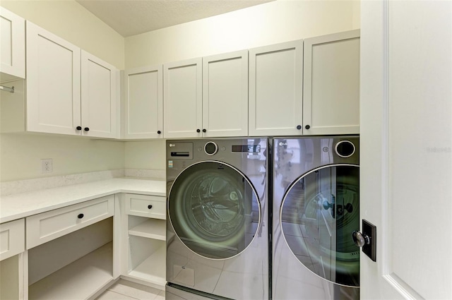 washroom with washing machine and clothes dryer, light tile patterned flooring, and cabinets