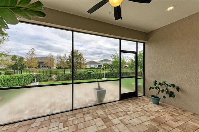 unfurnished sunroom with ceiling fan