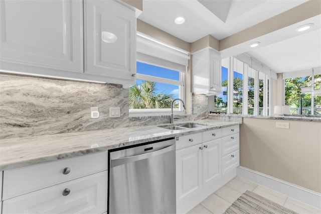 kitchen featuring decorative backsplash, white cabinetry, stainless steel dishwasher, and sink