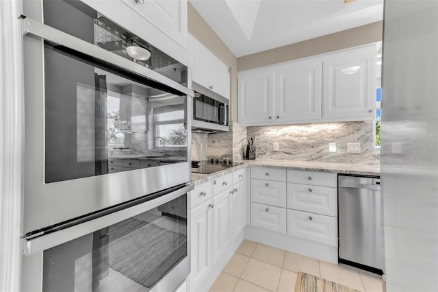 kitchen featuring light tile patterned floors, white cabinetry, backsplash, and appliances with stainless steel finishes