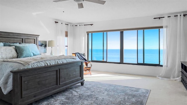 carpeted bedroom featuring a water view and ceiling fan