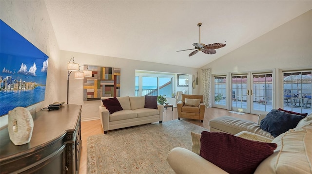 living room with ceiling fan, light hardwood / wood-style flooring, high vaulted ceiling, and french doors