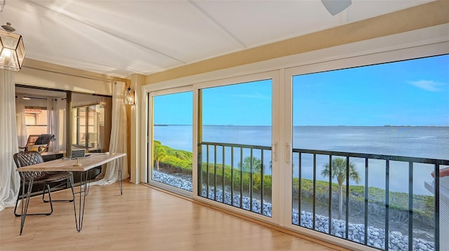 sunroom with ceiling fan and a water view