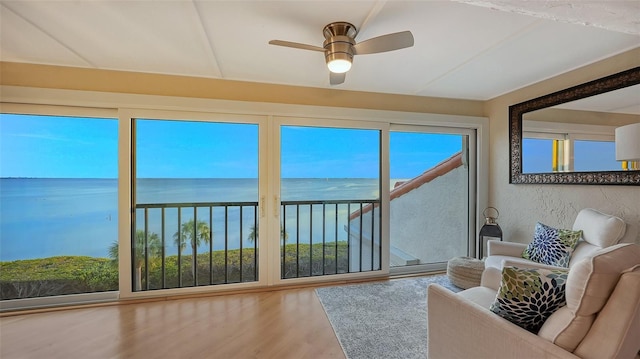 unfurnished sunroom featuring ceiling fan and a water view