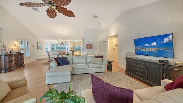 living room featuring lofted ceiling, light wood-type flooring, and ceiling fan with notable chandelier